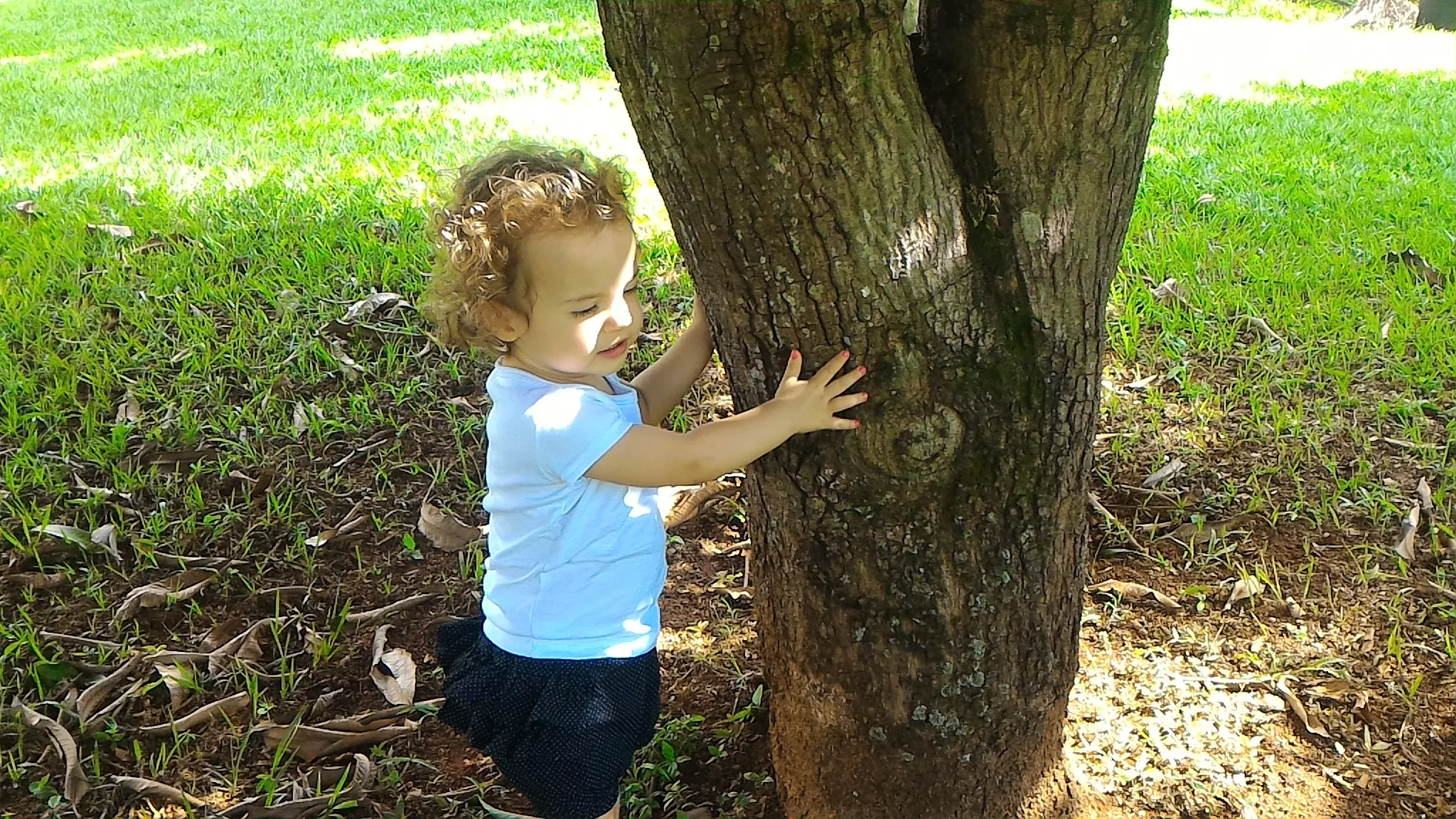 Helena explorando o mundo, ao lado de um árvore